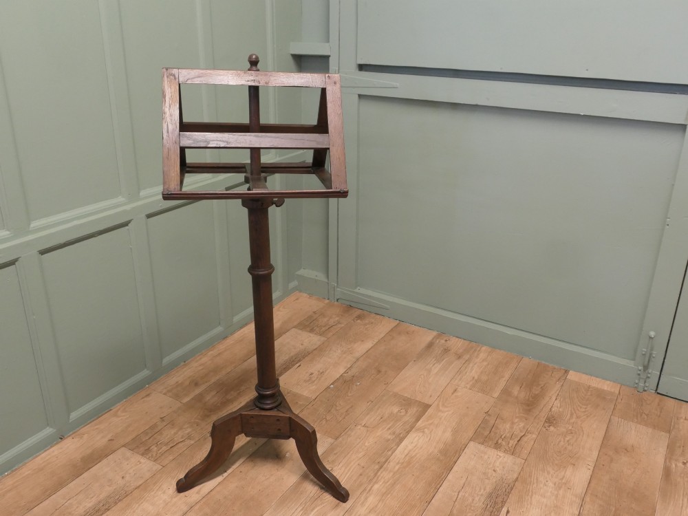 A 19th-century oak duet music stand featuring a double-sided adjustable rack resting on a turned column and tripod base. View VI