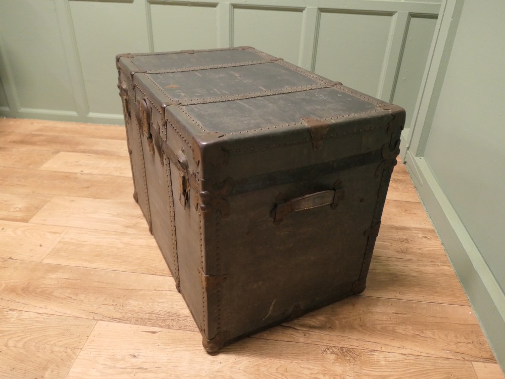 A rectangular dark grey vintage travel trunk with studded edges, metal corner protectors, and brass latch locks. View II
