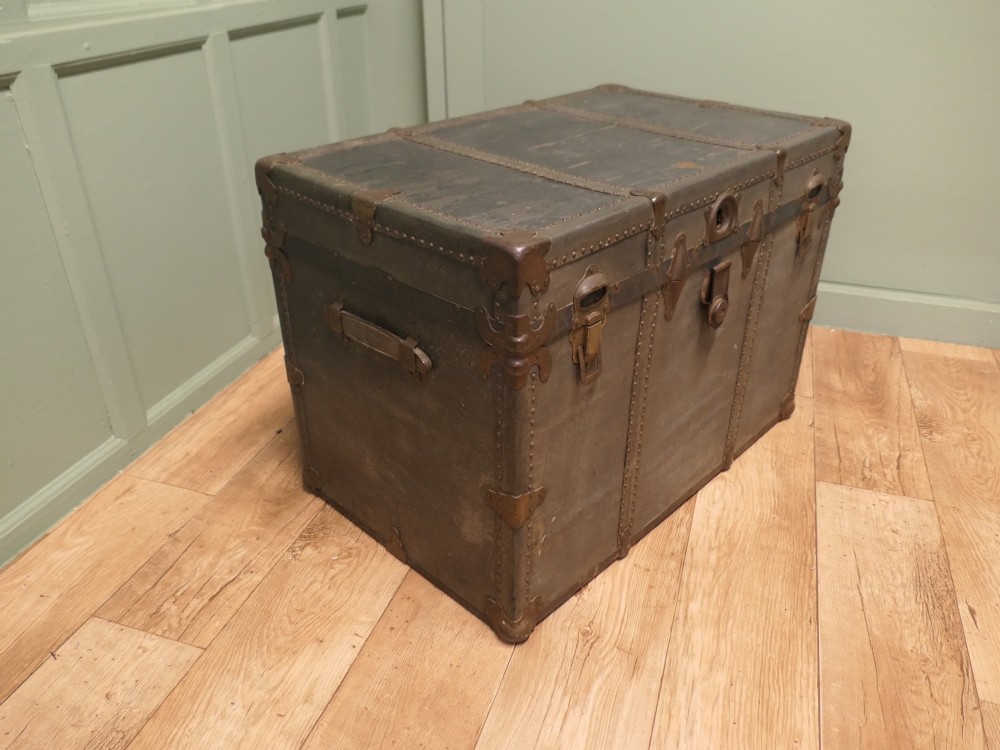 A rectangular dark grey vintage travel trunk with studded edges, metal corner protectors, and brass latch locks. View IV