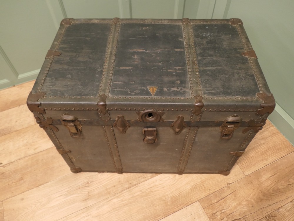 A rectangular dark grey vintage travel trunk with studded edges, metal corner protectors, and brass latch locks. View VI