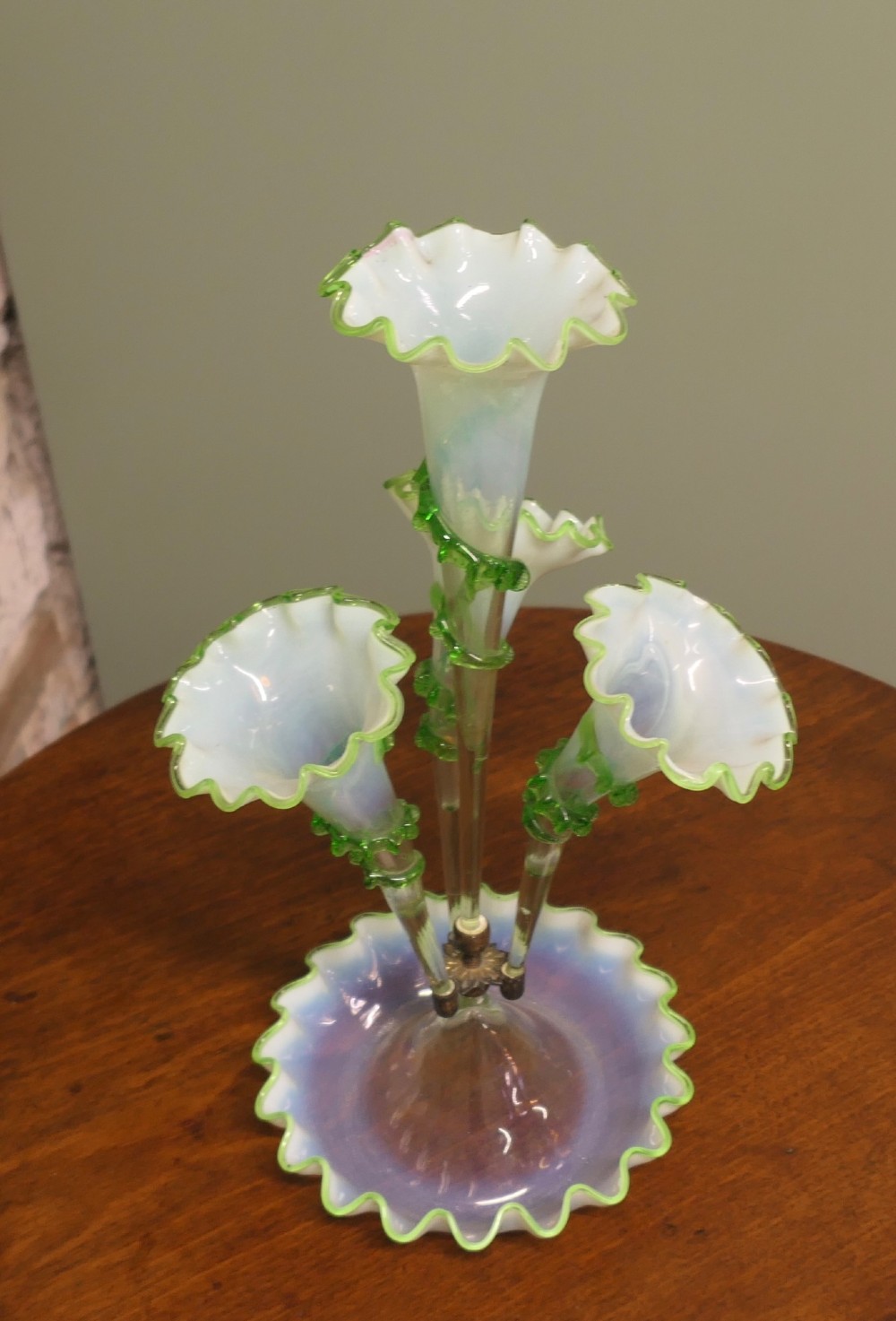 A nineteenth-century hand-blown uranium glass epergne featuring four crimped trumpet stems with applied green glass trailing mounted above an opalescent bowl base. View VI