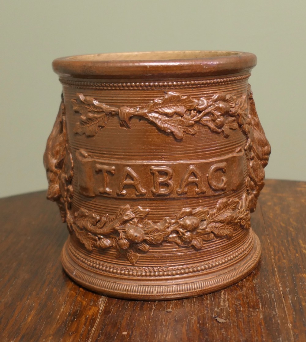A cylindrical brown glazed stoneware tobacco pot featuring raised lettering that reads TABAC surrounded by oak leaf and acorn garlands. View III