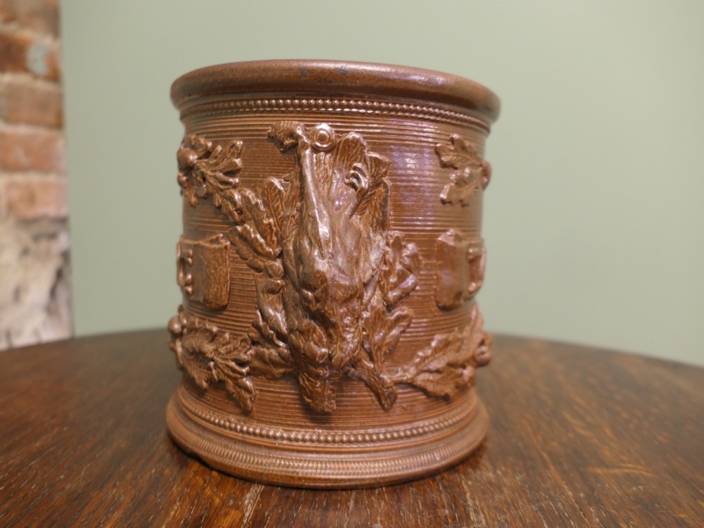A cylindrical brown glazed stoneware tobacco pot featuring raised lettering that reads TABAC surrounded by oak leaf and acorn garlands. View VI