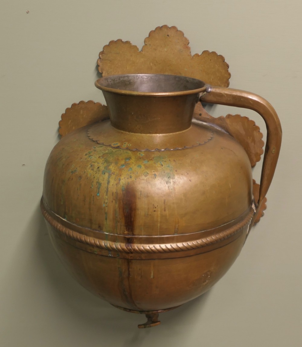 A hand-crafted copper and brass wall-mounted water reservoir featuring a scalloped backplate, rope-twist waist band, and lower tap. View III