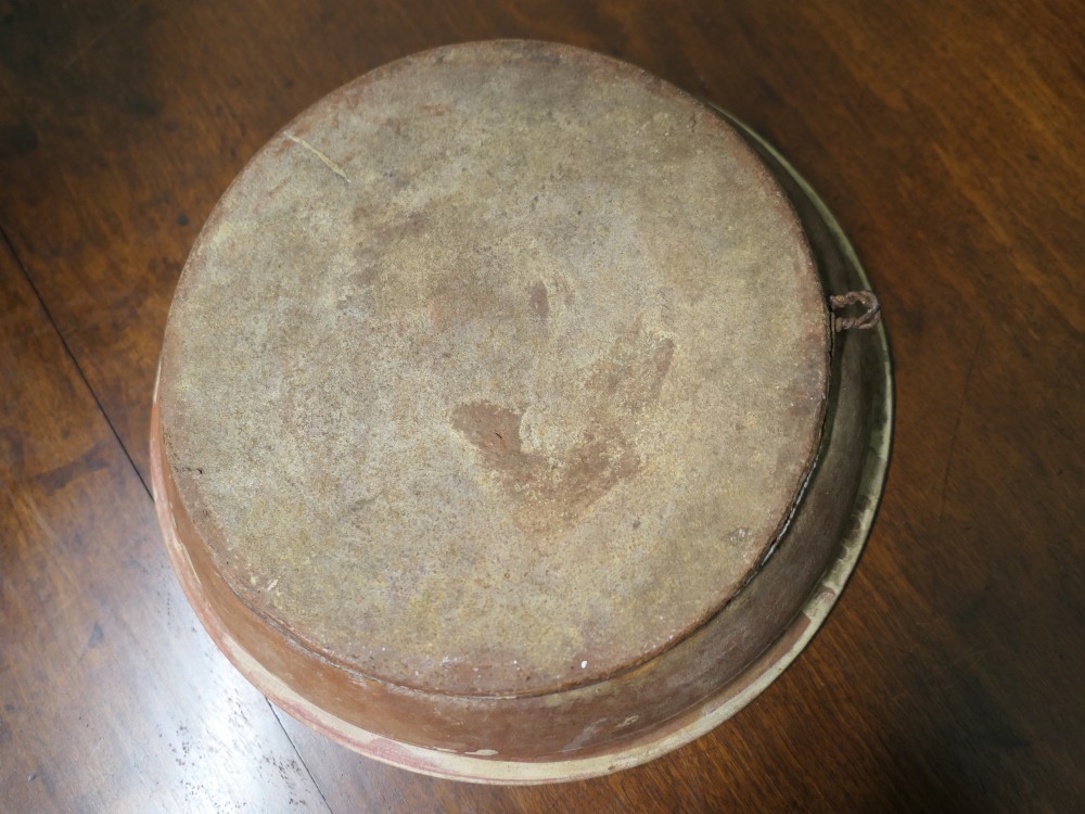 A large round cream-coloured French slipware terracotta bowl decorated with a blue scalloped rim and a naive central illustration of a hunter carrying a bow and hare. View VI