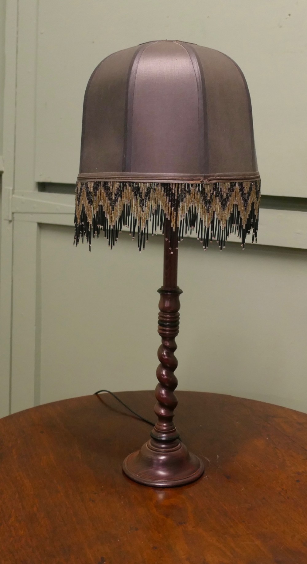 A wooden table lamp featuring a turned barley twist stem and a dark dome shade adorned with glass bead fringe. View VII