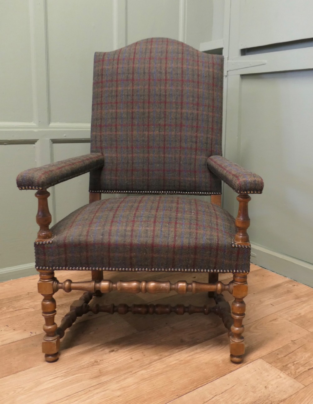 An upholstered high-back armchair with tweed plaid fabric, brass studding, and turned oak legs with stretchers. View II