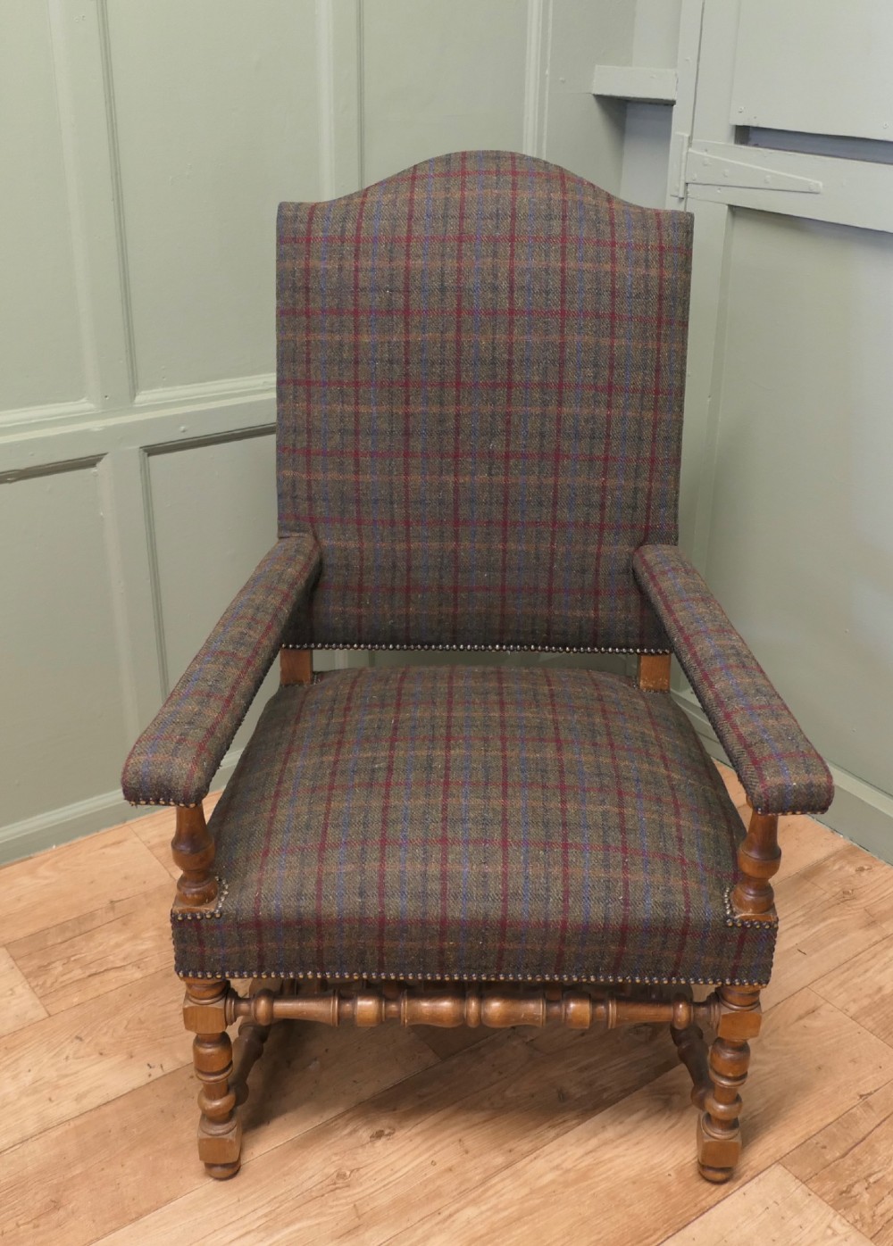 An upholstered high-back armchair with tweed plaid fabric, brass studding, and turned oak legs with stretchers. View III