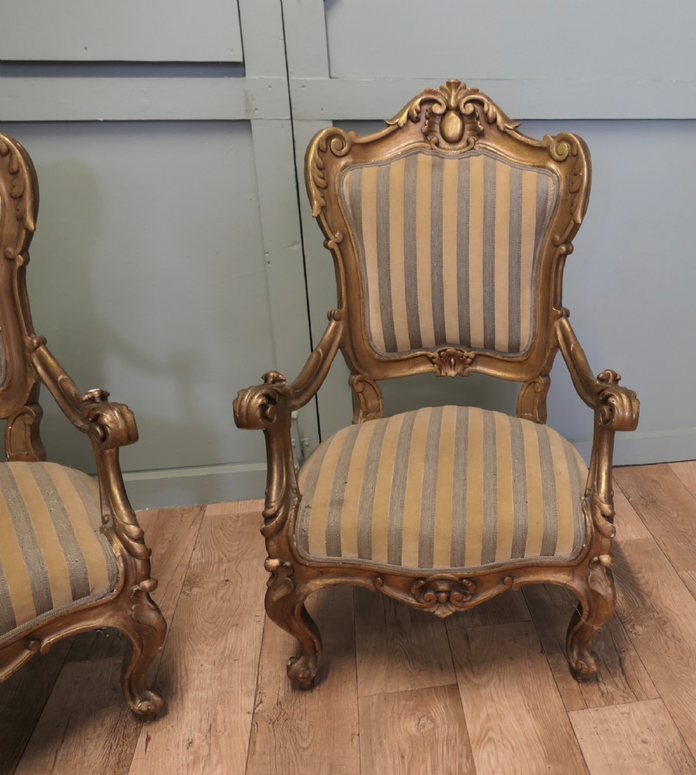 A pair of ornate Italian Rococo style armchairs with carved giltwood frames and grey and gold striped upholstery. View III