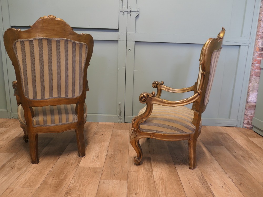 A pair of ornate Italian Rococo style armchairs with carved giltwood frames and grey and gold striped upholstery. View V