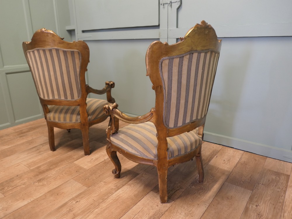 A pair of ornate Italian Rococo style armchairs with carved giltwood frames and grey and gold striped upholstery. View VI
