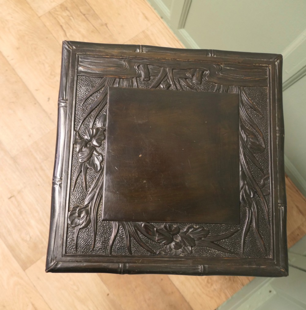 A dark brown Arts and Crafts lamp table featuring carved iris floral motifs, bamboo moulding along the rim, flared lower legs, and an undertier. View IV