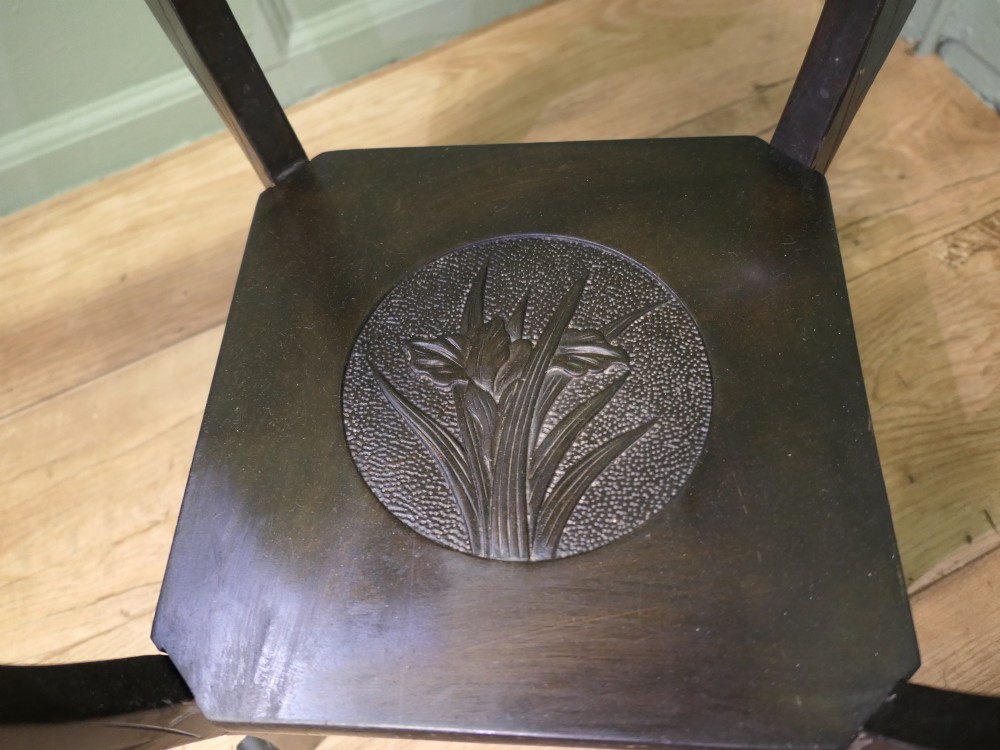 A dark brown Arts and Crafts lamp table featuring carved iris floral motifs, bamboo moulding along the rim, flared lower legs, and an undertier. View V