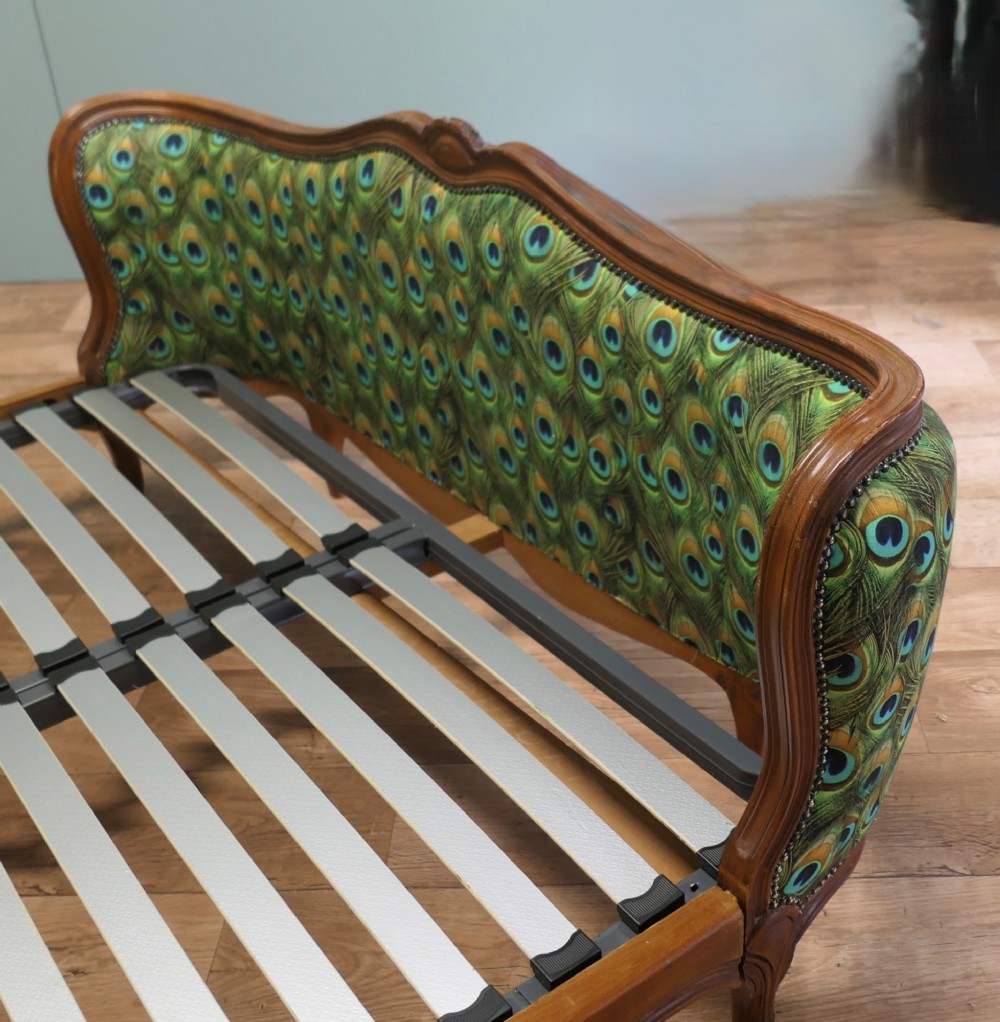 A French Louis XV style double bed frame featuring carved wooden borders, a padded headboard, and a curved corbeille footboard upholstered in green peacock feather patterned fabric with studding. View III
