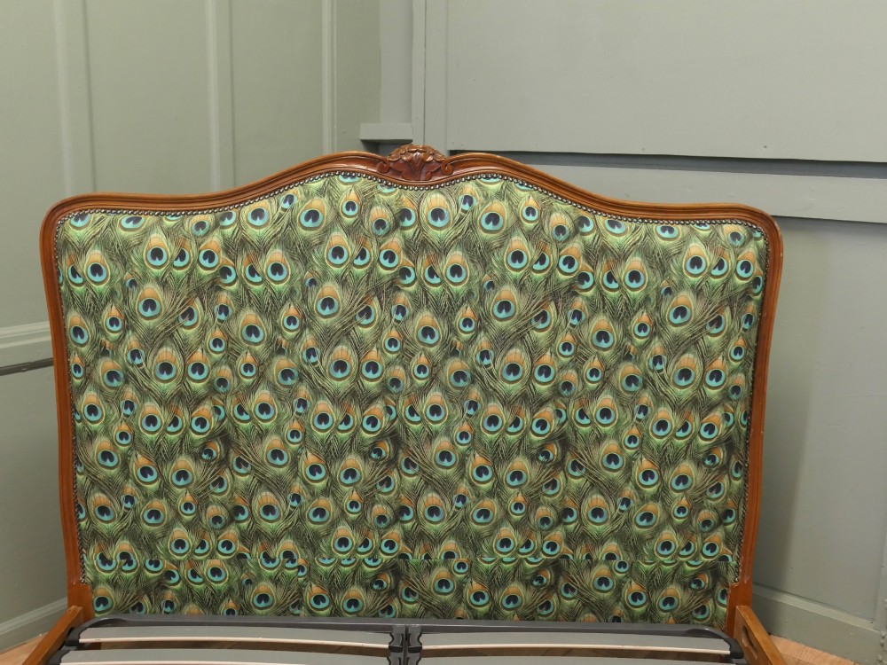 A French Louis XV style double bed frame featuring carved wooden borders, a padded headboard, and a curved corbeille footboard upholstered in green peacock feather patterned fabric with studding. View V
