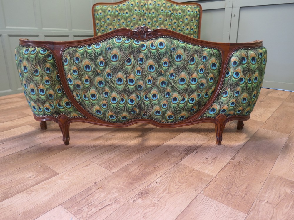 A French Louis XV style double bed frame featuring carved wooden borders, a padded headboard, and a curved corbeille footboard upholstered in green peacock feather patterned fabric with studding. View VII