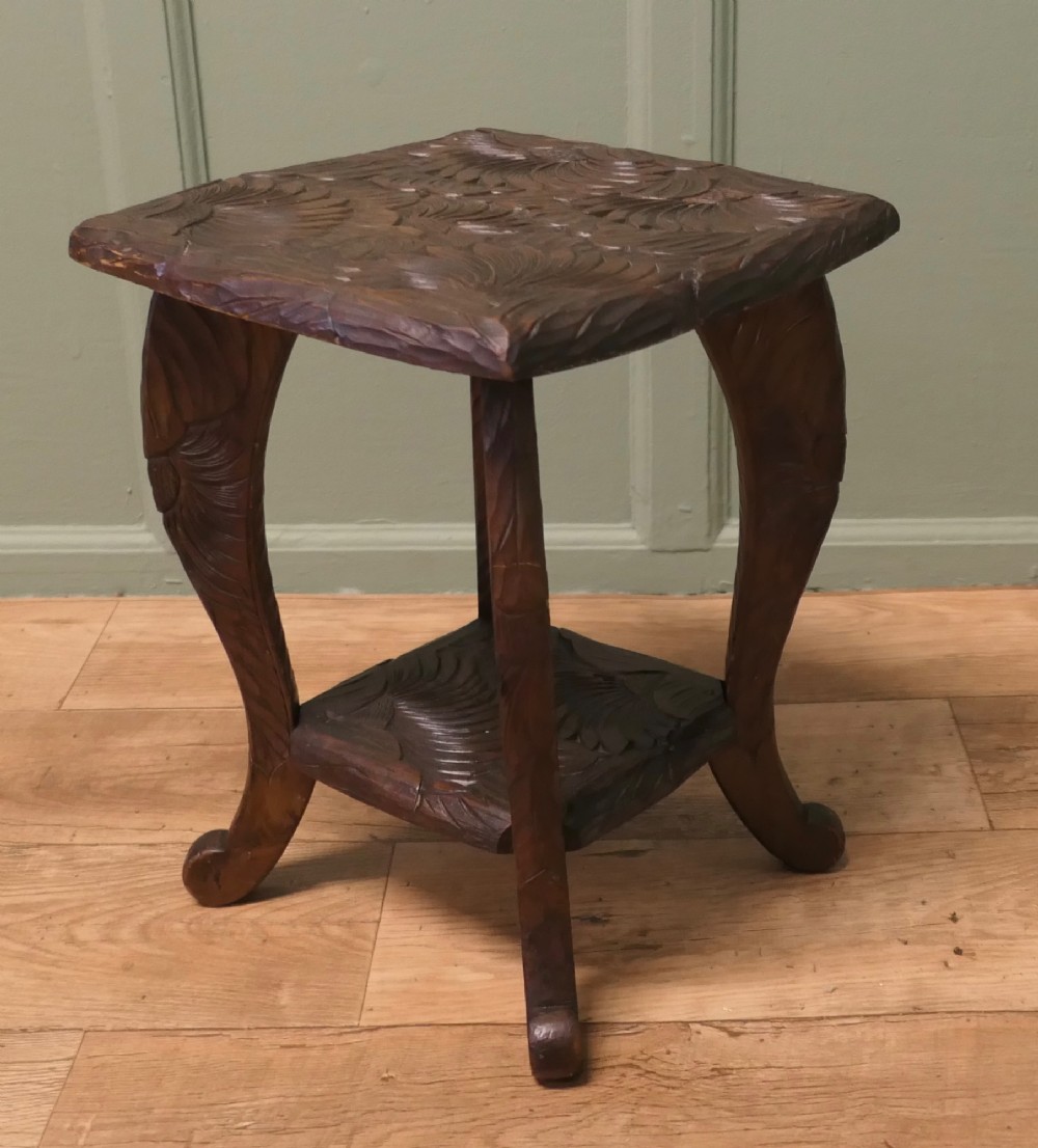 A square dark oak Arts and Crafts side table featuring hand-carved sunflower motifs across the top and lower shelf, supported by four gently curved legs. View III