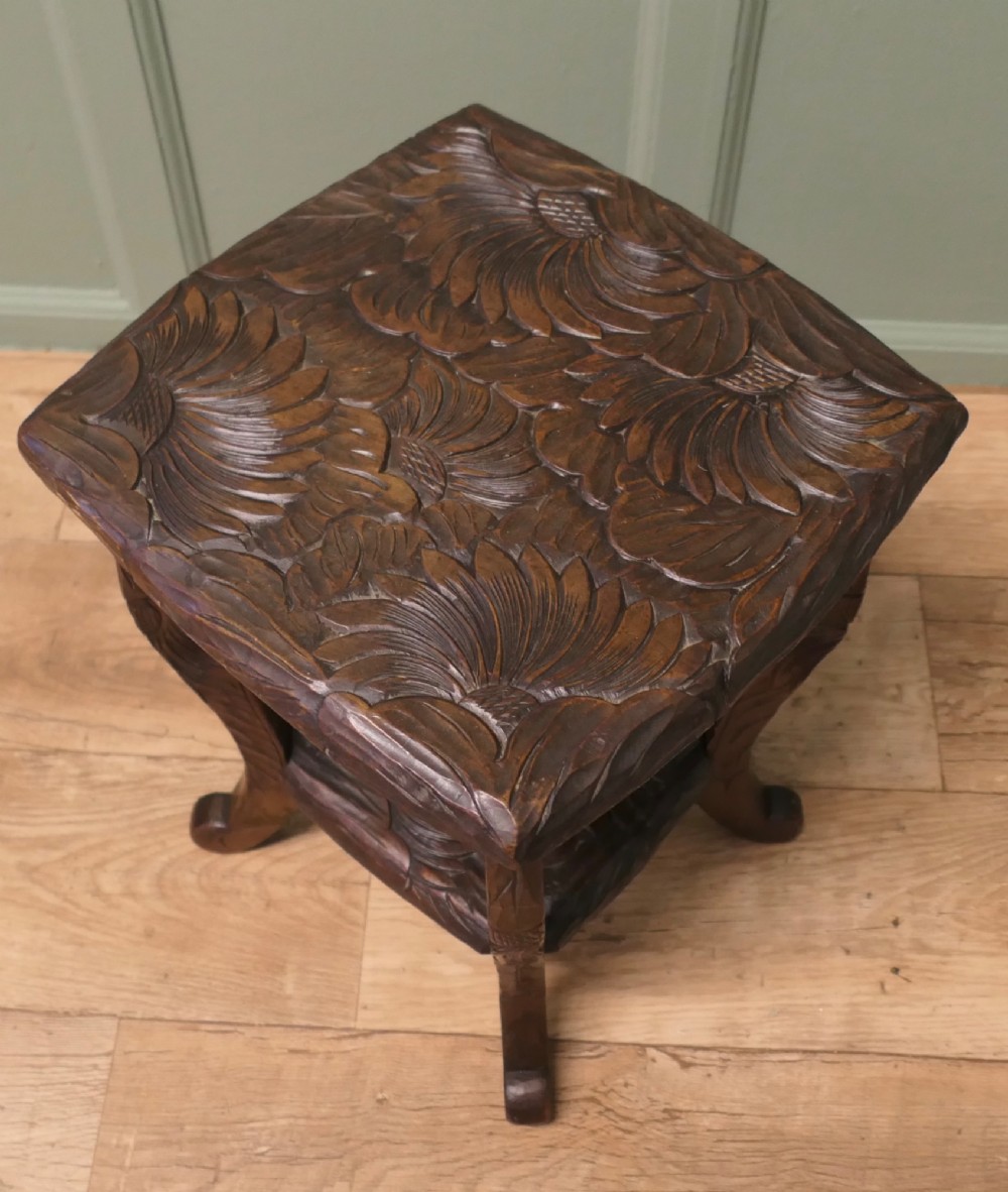 A square dark oak Arts and Crafts side table featuring hand-carved sunflower motifs across the top and lower shelf, supported by four gently curved legs. View IV