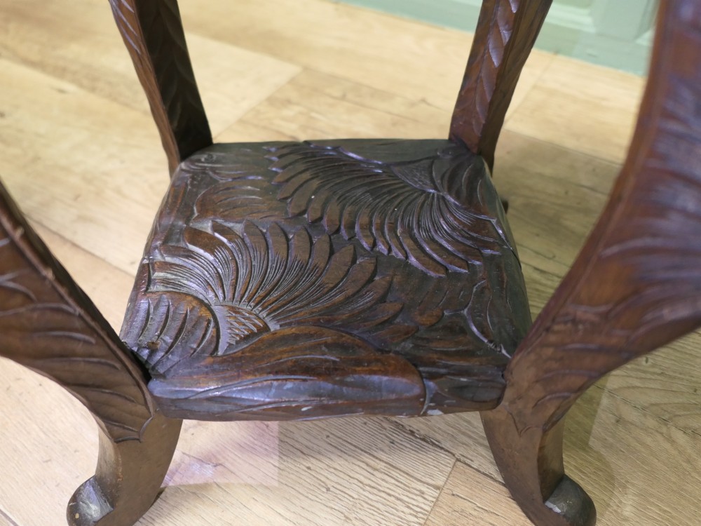 A square dark oak Arts and Crafts side table featuring hand-carved sunflower motifs across the top and lower shelf, supported by four gently curved legs. View VI