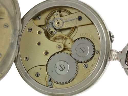 fig 2. An open-faced Longines pocket watch with a silver case, white enamel dial, black Arabic numerals, and a subsidiary seconds dial.
