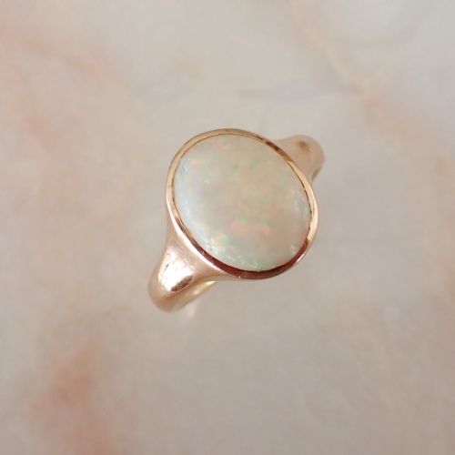 fig 1. An antique Victorian 18ct yellow gold ring featuring an oval cabochon opal in a smooth bezel setting.