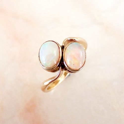 fig 1. An Edwardian gold Toi et Moi ring featuring two oval cabochon opals set side by side on a fluid bypass band.