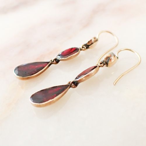 fig 1. A pair of antique gold drop earrings featuring three articulated faceted deep red garnets in round, oval, and pear shapes.