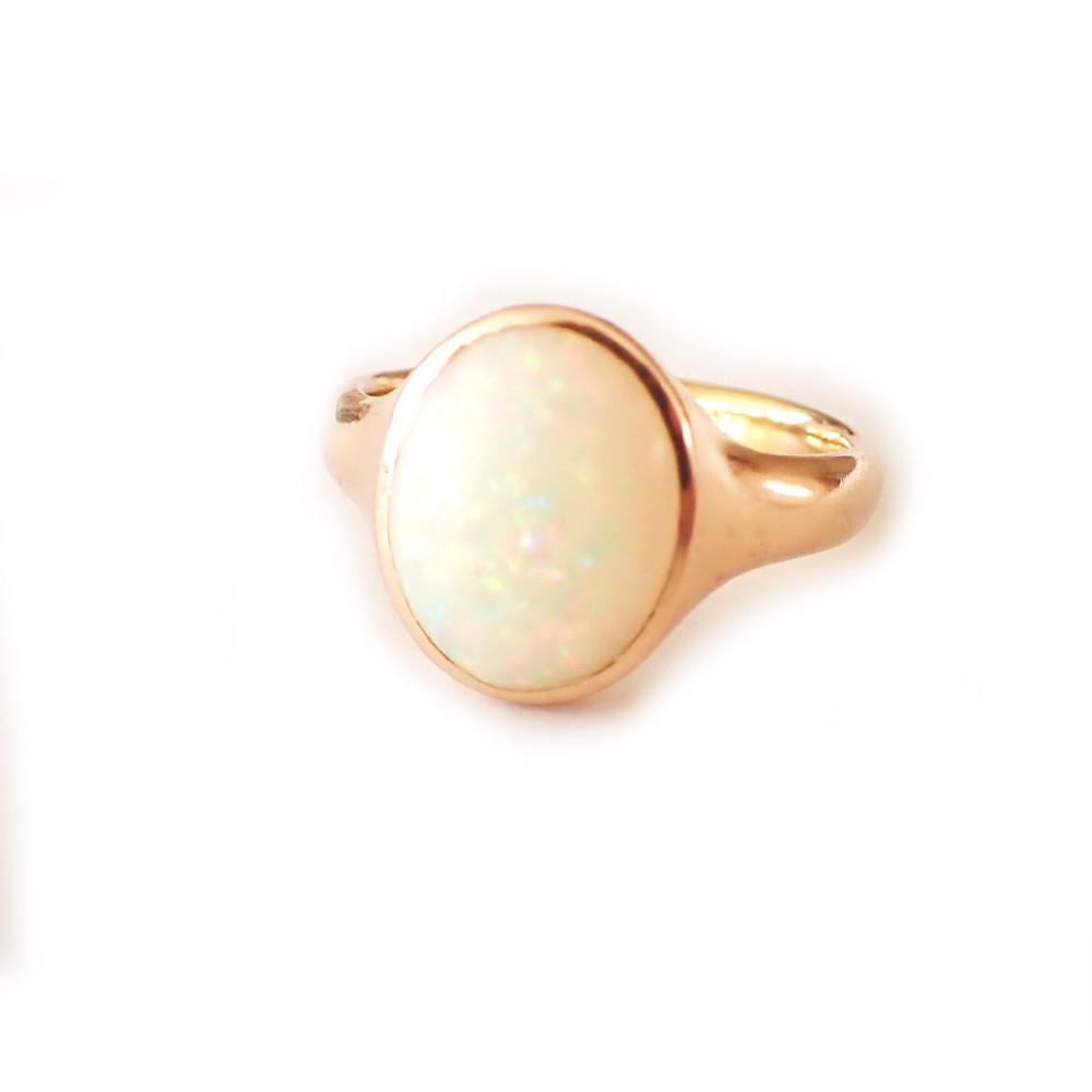 An antique Victorian 18ct yellow gold ring featuring an oval cabochon opal in a smooth bezel setting.