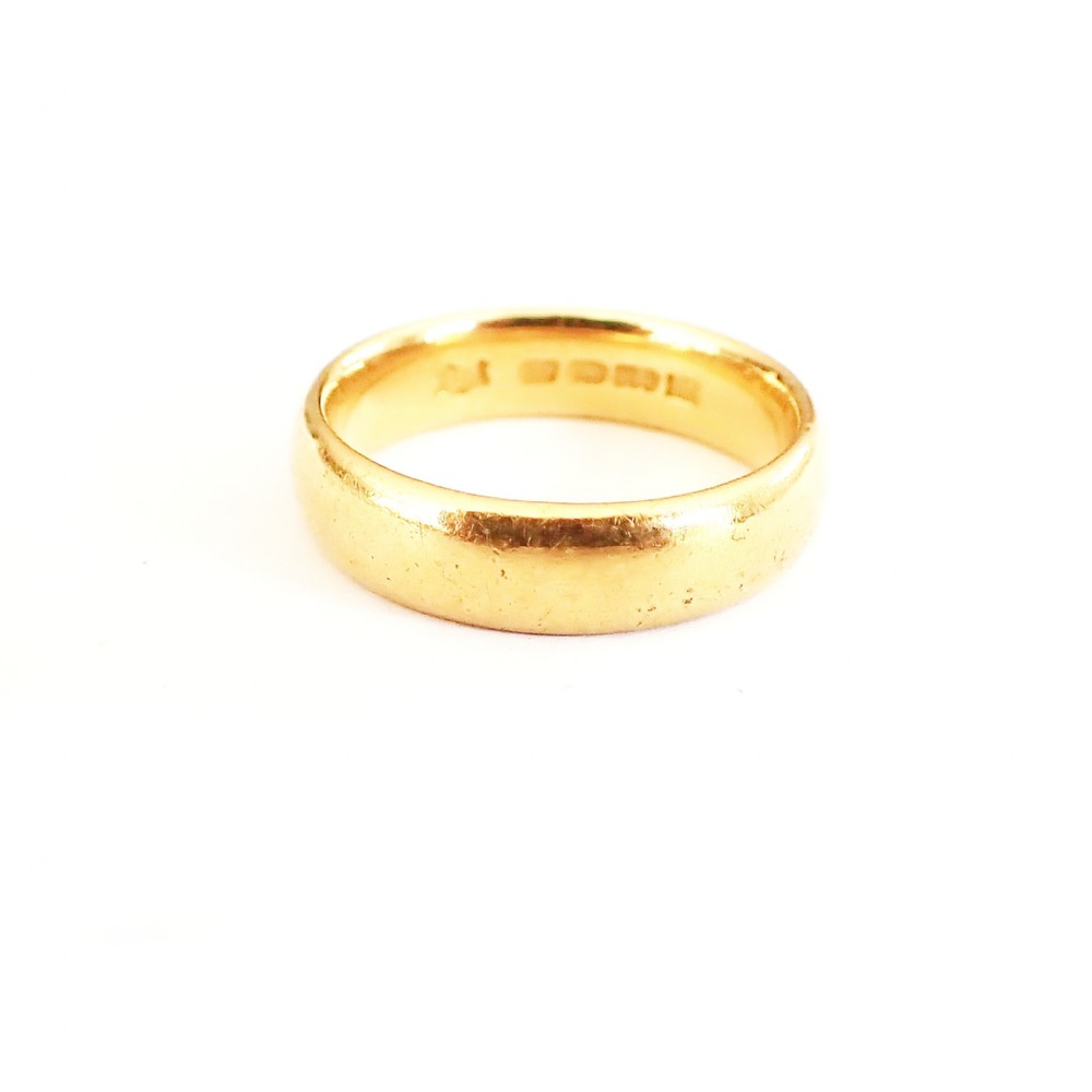 A solid 22ct yellow gold band ring with visible internal hallmarks against a plain white background.