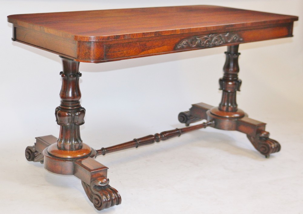 A William IV rosewood centre table featuring a rectangular top with rounded corners, a carved frieze, turned end supports, a low stretcher, and scroll feet. View II