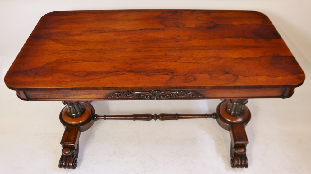 A William IV rosewood centre table featuring a rectangular top with rounded corners, a carved frieze, turned end supports, a low stretcher, and scroll feet. View III
