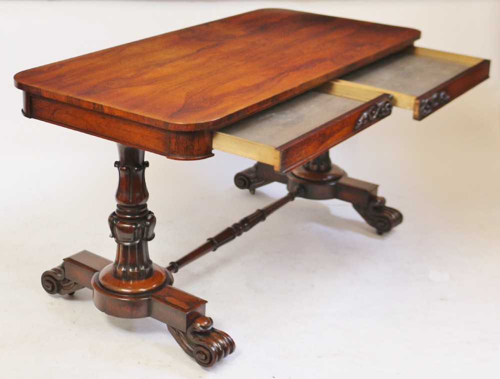 A William IV rosewood centre table featuring a rectangular top with rounded corners, a carved frieze, turned end supports, a low stretcher, and scroll feet. View IV