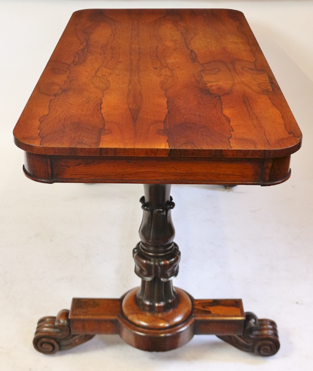 A William IV rosewood centre table featuring a rectangular top with rounded corners, a carved frieze, turned end supports, a low stretcher, and scroll feet. View VI