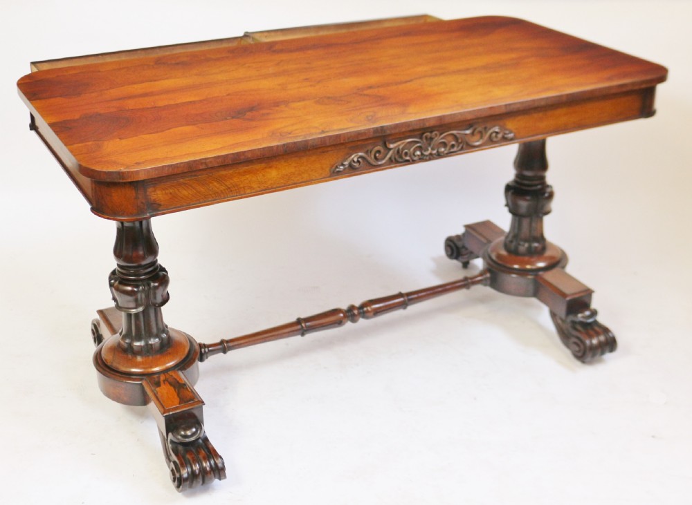 A William IV rosewood centre table featuring a rectangular top with rounded corners, a carved frieze, turned end supports, a low stretcher, and scroll feet. View VII