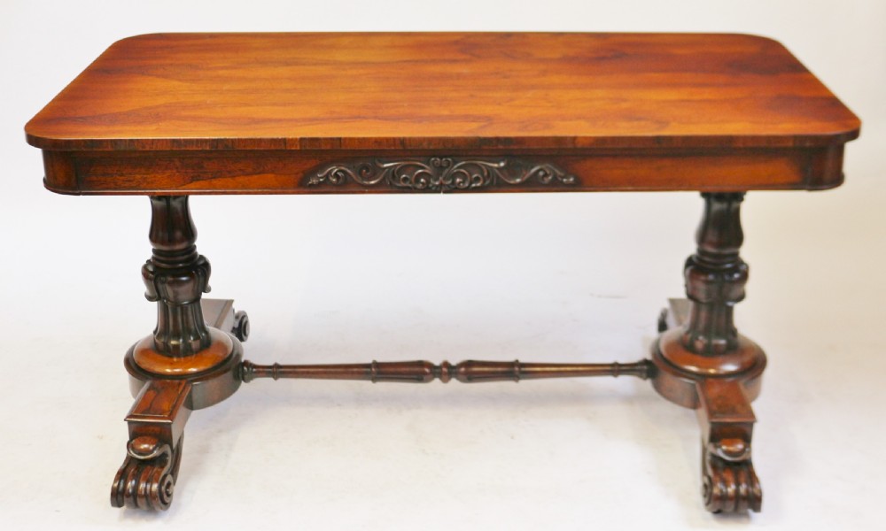 A William IV rosewood centre table featuring a rectangular top with rounded corners, a carved frieze, turned end supports, a low stretcher, and scroll feet. View X