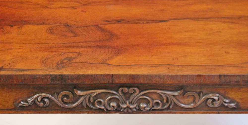 A William IV rosewood centre table featuring a rectangular top with rounded corners, a carved frieze, turned end supports, a low stretcher, and scroll feet. View XI