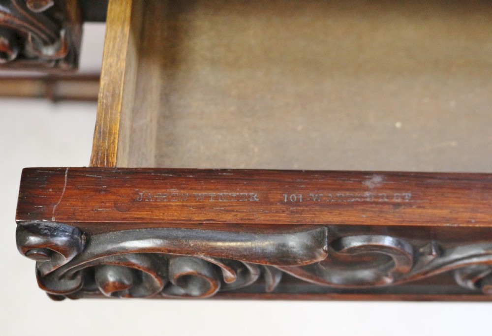 A William IV rosewood centre table featuring a rectangular top with rounded corners, a carved frieze, turned end supports, a low stretcher, and scroll feet. View XII