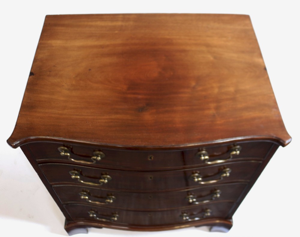 A George III mahogany serpentine chest of drawers featuring four drawers with brass swan-neck handles and bracket feet. View IV