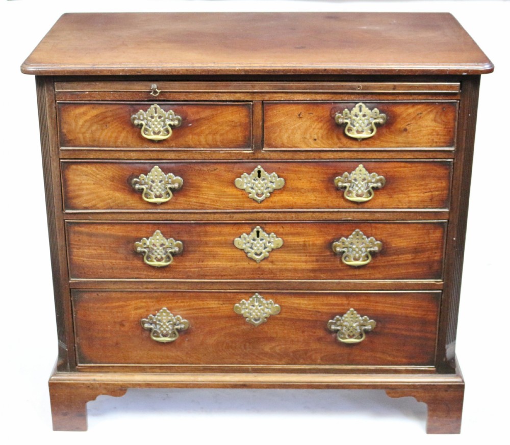 A George III mahogany chest of drawers featuring a pull-out brushing slide, two short drawers over three long graduated drawers with decorative brass handles, raised on bracket feet.