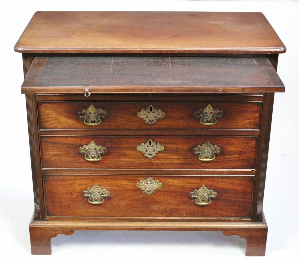 A George III mahogany chest of drawers featuring a pull-out brushing slide, two short drawers over three long graduated drawers with decorative brass handles, raised on bracket feet. View II