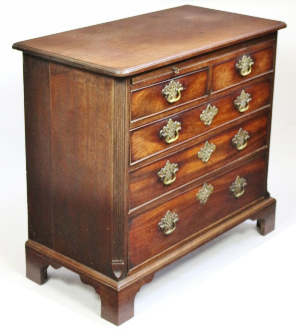 A George III mahogany chest of drawers featuring a pull-out brushing slide, two short drawers over three long graduated drawers with decorative brass handles, raised on bracket feet. View III