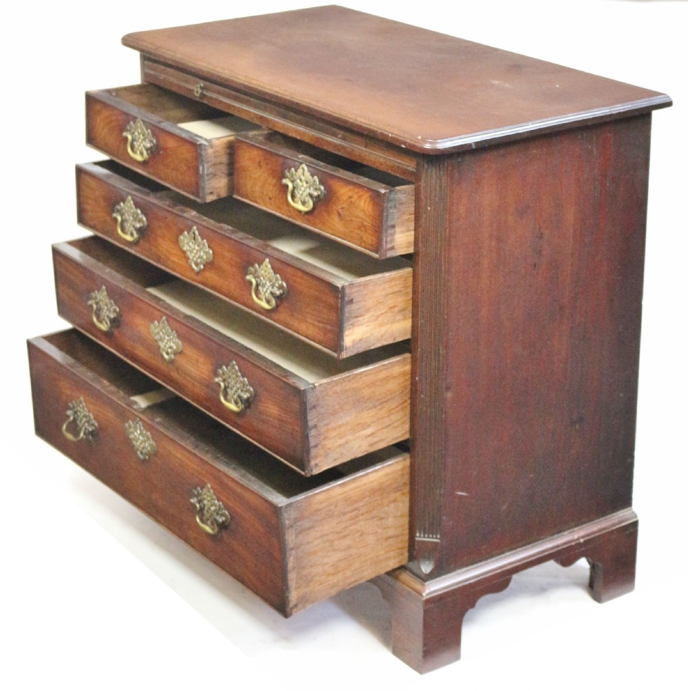 A George III mahogany chest of drawers featuring a pull-out brushing slide, two short drawers over three long graduated drawers with decorative brass handles, raised on bracket feet. View IV