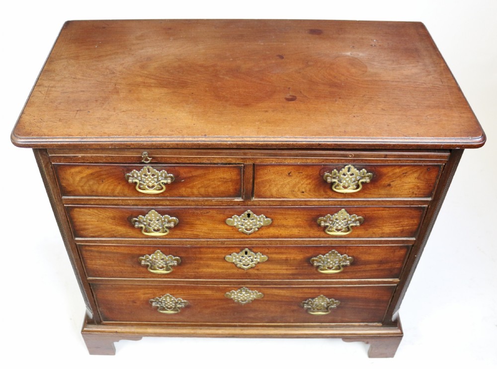 A George III mahogany chest of drawers featuring a pull-out brushing slide, two short drawers over three long graduated drawers with decorative brass handles, raised on bracket feet. View V