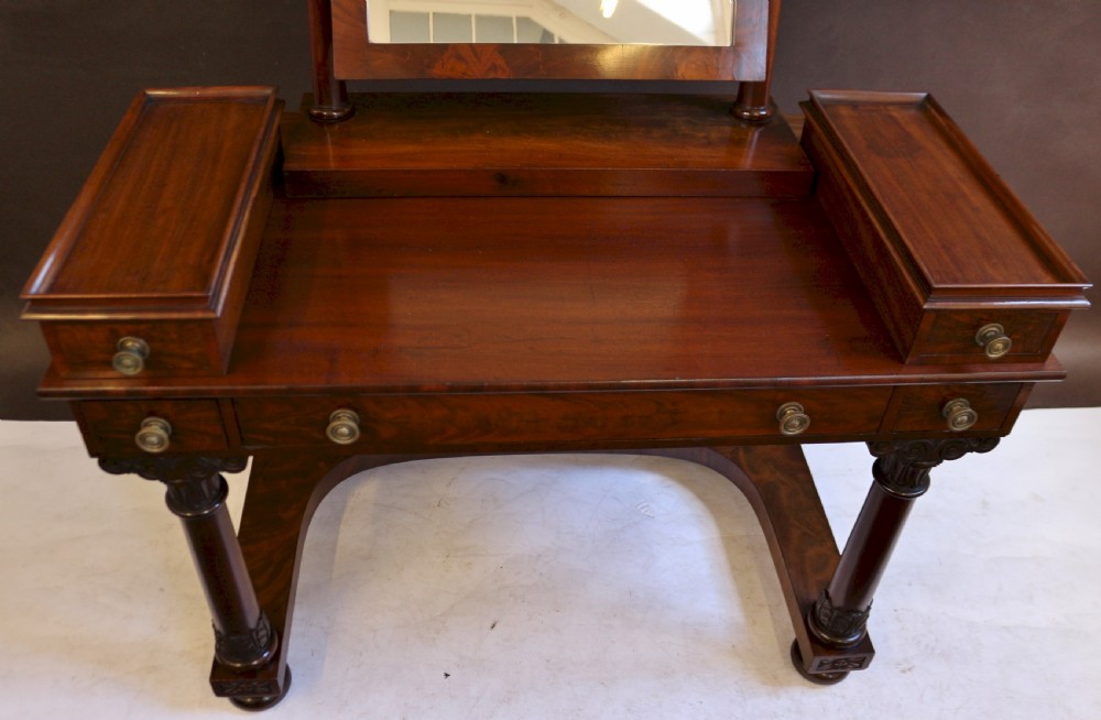 A William IV mahogany dressing table featuring an arched swivel mirror, brass sconces, upper drawers, and carved front columns on a plinth base. View VI