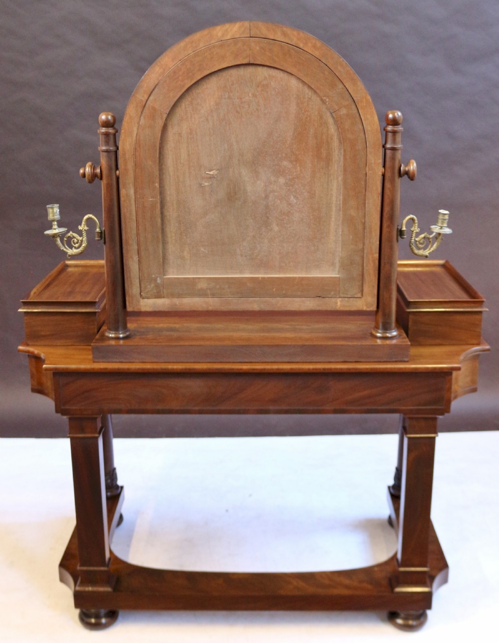 A William IV mahogany dressing table featuring an arched swivel mirror, brass sconces, upper drawers, and carved front columns on a plinth base. View X