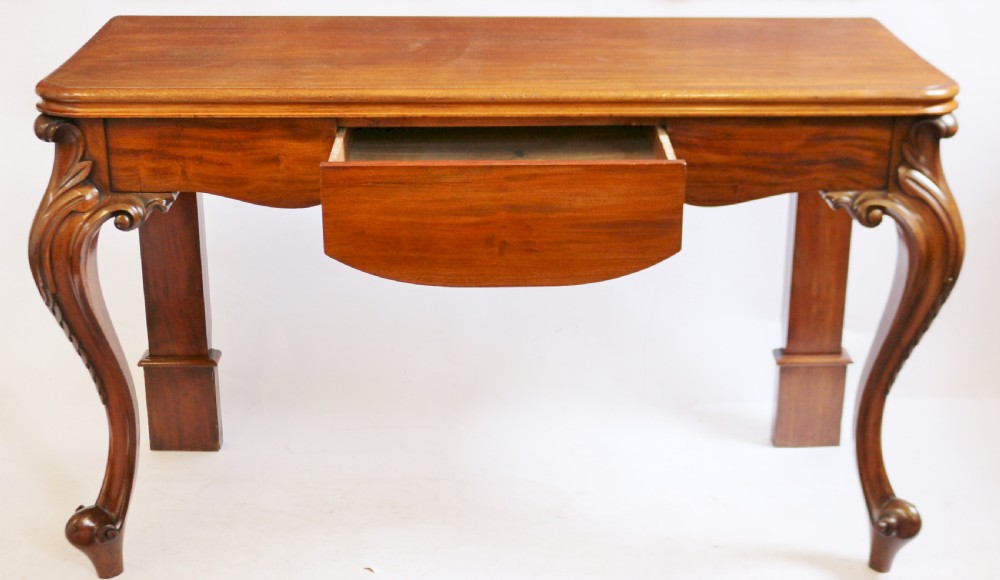 A Victorian mahogany console table featuring carved cabriole front legs with scroll feet, a shaped front apron, and a flat polished surface. View II