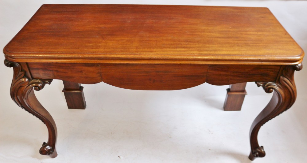 A Victorian mahogany console table featuring carved cabriole front legs with scroll feet, a shaped front apron, and a flat polished surface. View III
