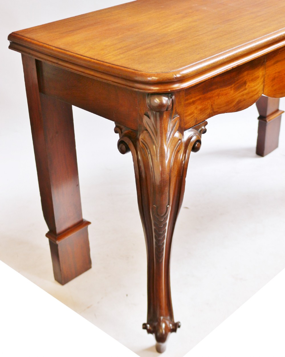 A Victorian mahogany console table featuring carved cabriole front legs with scroll feet, a shaped front apron, and a flat polished surface. View VIII