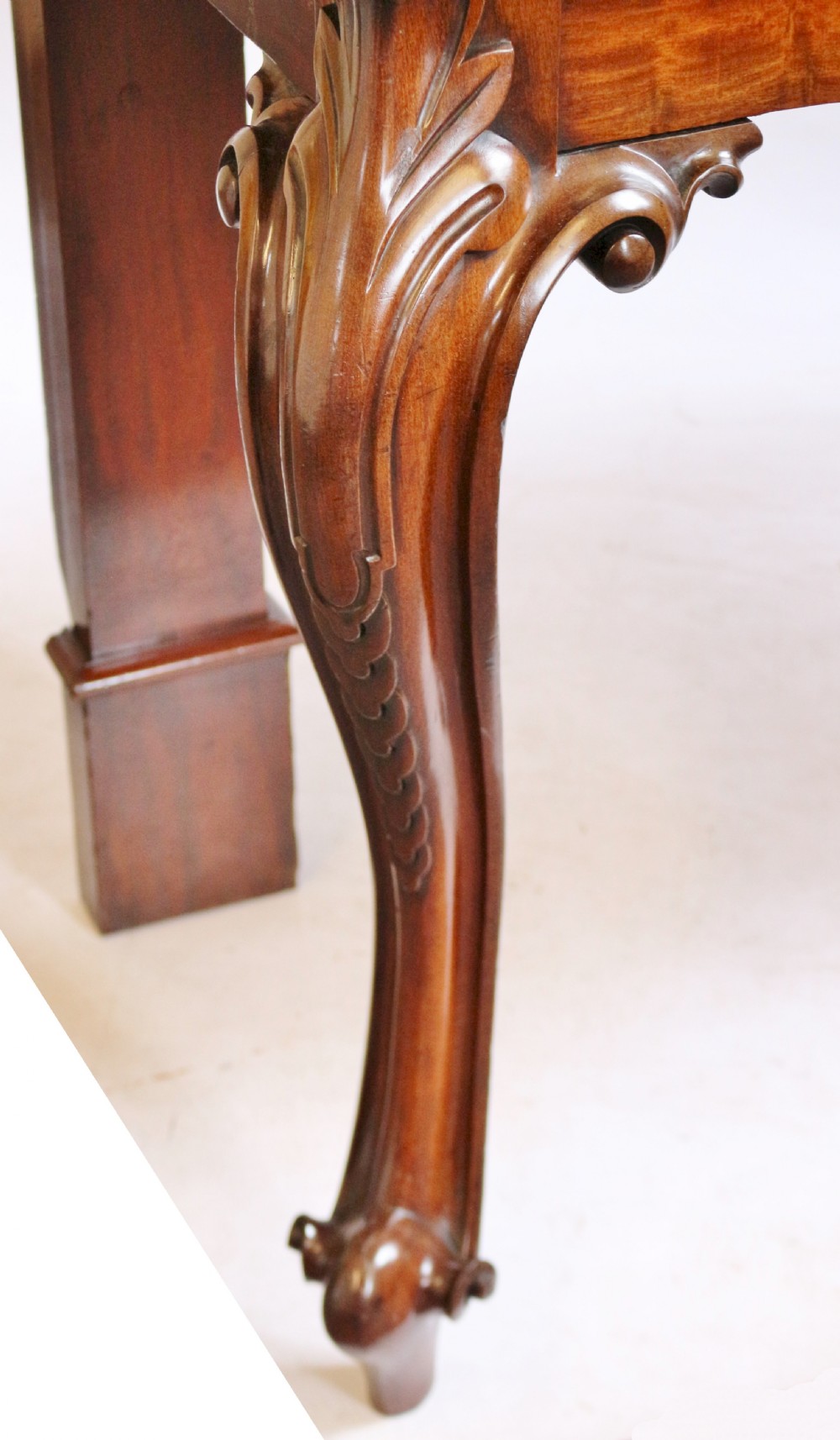 A Victorian mahogany console table featuring carved cabriole front legs with scroll feet, a shaped front apron, and a flat polished surface. View IX