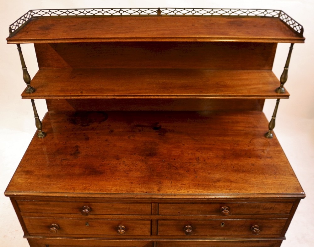 A Regency mahogany chiffonier with a two-tier brass-galleried shelf unit above a fitted writing drawer and two-door cabinet base. View VI